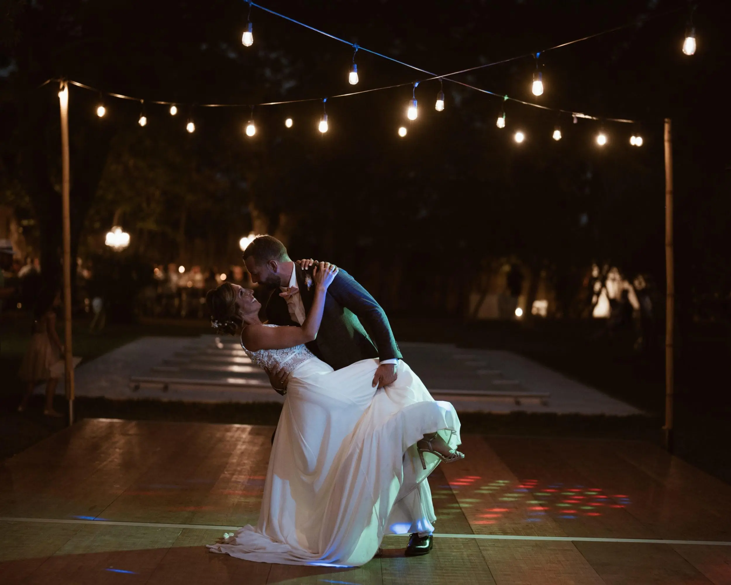 Mariés effectuant leur ouverture de bal sous des guirlandes guinguette en location à Avignon, illuminant la scène avec une ambiance romantique.